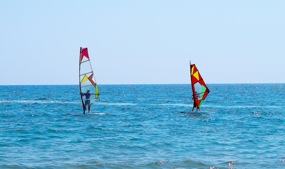 Two windsurfers learning on the ocean