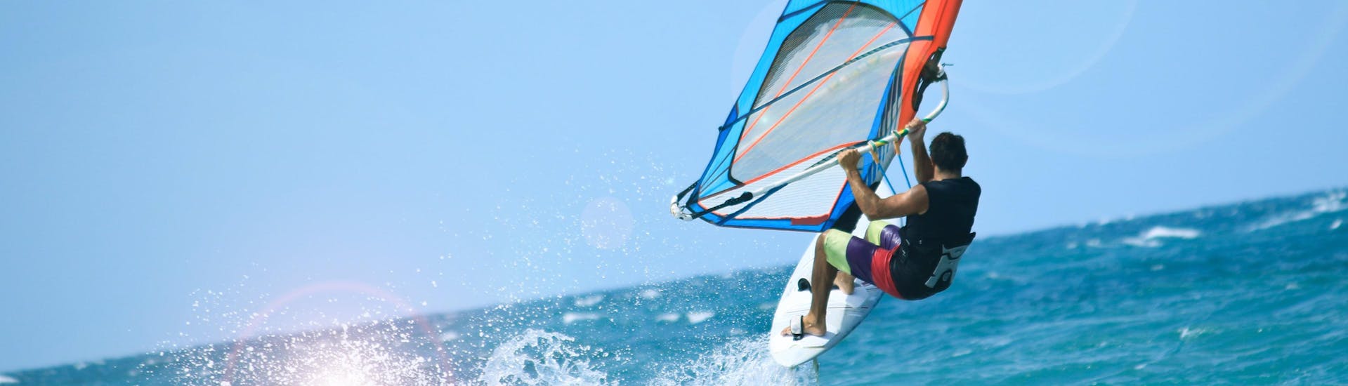 Un chico hace un curso de windsurf en el popular destino de vacaciones de Área Metropolitana de Lisboa.