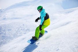 A young snowboarder is gliding down the slope while taking part in Snowboarding Lessons for Kids & Adults for Beginners with the ski school DSV Skischule Züschen.