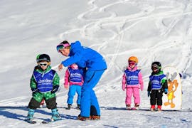Un grupo de niños hace un ejercicio durante las Clases de esquí para niños "Polar Bears" (3-5 años) con Altitude Ski School Verbier & Gstaad.