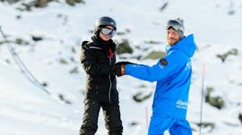 Uno sciatore e il suo maestro di sci ridono durante le lezioni private di snowboard per adulti a Verbier con la scuola di sci Altitude Verbier & Gstaad.
