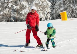 Un maestro di sci sta aiutando un bambino a fare le prime discese, le lezioni private di sci per bambini - tutti i livelli della Scuola di Sci Abetone permettono al bambino di essere seguito individualmente.