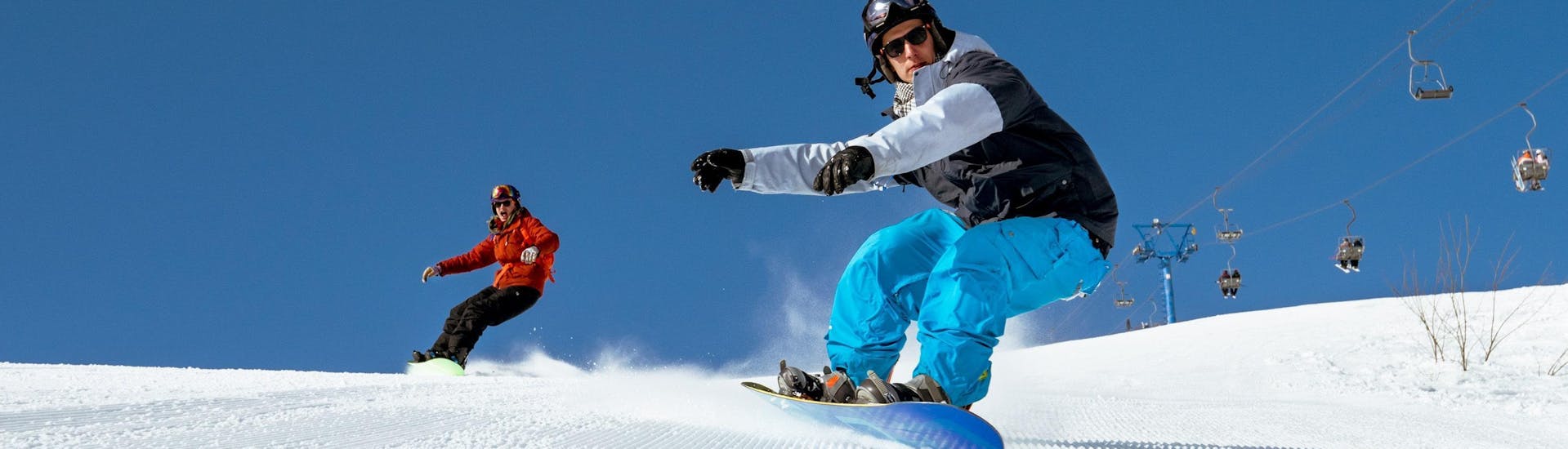 Un maestro di snowboard sta aiutando un signore a migliorare la sua tecnica, le lezioni private di snowboard per bambini e adulti - tutti i livelli  della Scuola di Scia Abetone gli permettono di essere seguito individualmente.