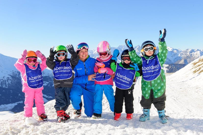 Vijf kinderen en hun leraar juichen op de berg tijdens de kinderskilessen "ijsbeer" voor alle niveaus bij skischule Altitude Grindelwald en Wengen.