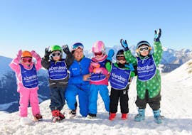 Fünf Kinder und ihr Skilehrer jubeln am Berg beim Kinder-Skikurs "Eisbär" für alle Stufen mit der Skischule Altitude Grindelwald und Wengen.