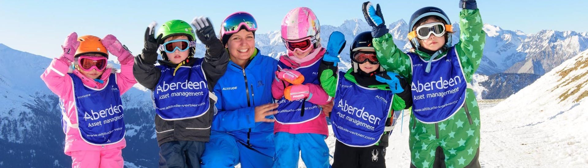 Five children and their instructor are cheering on the mountain during kids ski lessons "polar bear" for all levels with skischule Altitude Grindelwald and Wengen.