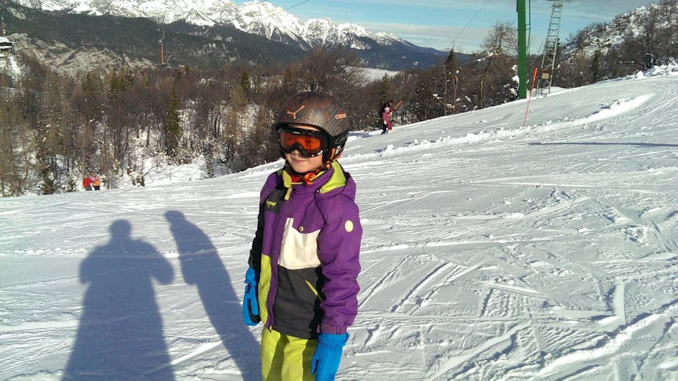 Ein Kind erfreut sich am maßgeschneiderten Privat-Skikurs für Kinder und an der vollen Aufmerksamkeit seines Skilehrers von der Slovenia Ski School - Für alle Levels.