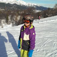 Tijdens de privé-skilessen voor kinderen - alle niveaus luistert een kind aandachtig naar zijn skileraar van skischool Slovenië.