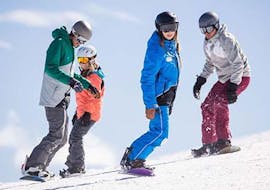 Four snowboarders are riding down a shallow slope during their kids and adult snowboarding lessons for all levels with skischule Altitude in Grindelwald and Wengen.