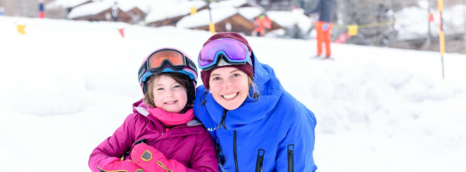 Ein Skilehrer und ein Kind lächeln in die Kamera während einer privaten Skistunde für Kinder mit der Skischule Altitude in Grindelwald und Wengen.