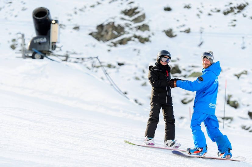 An instructor is teaching a snowboarder the right stance during his private snowboarding lessons for kids and adults of all levels with skischool Altitude in Grindelwald and Wengen.