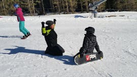An instructor is showing a child how to snowboard during its kids and adult snowboarding lessons for first timers with skischule Oberharz in Wurmberg.