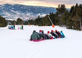 Eine Gruppe von Freunden amüsiert sich auf der verschneiten Piste mit der neuesten Attraktion der Skischule ESI Font Romeu, dem Snake Gliss.