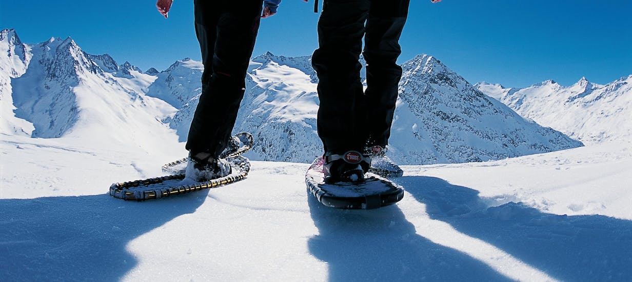 twee personen met sneeuwschoenen staan bovenop een berg.