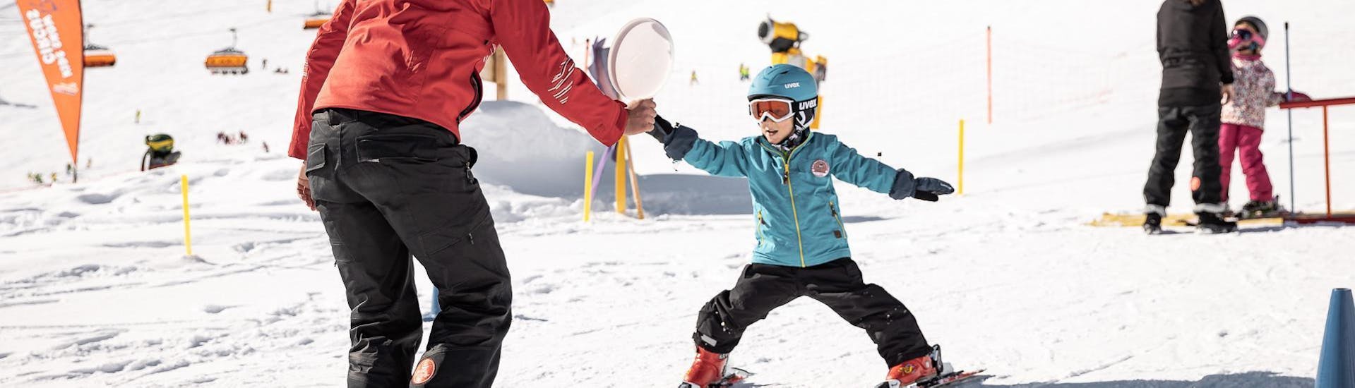 Un jeune enfant fait ses premiers pas sur des skis pendant les cours de ski pour enfants (3-4 ans) - premiers pas avec un moniteur expérimenté de l'école de ski et de snowboard de Vacancia.