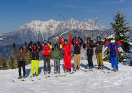 Les skieurs accompagnés du moniteur de ski sur la montagne et sourient à la caméra pendant les cours de ski pour adultes - débutants de l'école de ski S4 Snowsports Fieberbrunn.