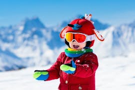 Un enfant sourit joyeusement à la caméra dans un paysage de montagne pendant les cours de snowboard pour enfants (à partir de 7 ans) - débutant de l'école de ski S4 Snowsports Fieberbrunn.