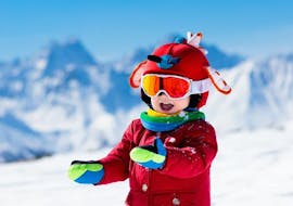 A child smiles happily into the camera in the mountain landscape during the snowboarding lessons for kids (from 7 years) - beginner of the ski school S4 Snowsports Fieberbrunn.