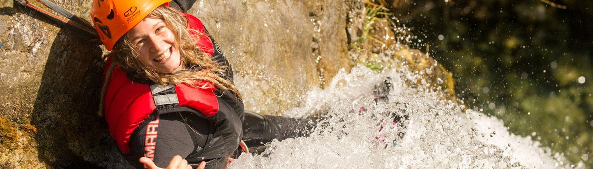 Une fille sourit à l'appareil photo pendant l'aventure de canyoning dans le Palvico d'Arco au lac de Garde avec Mmove - Into Nature Garda Lake.