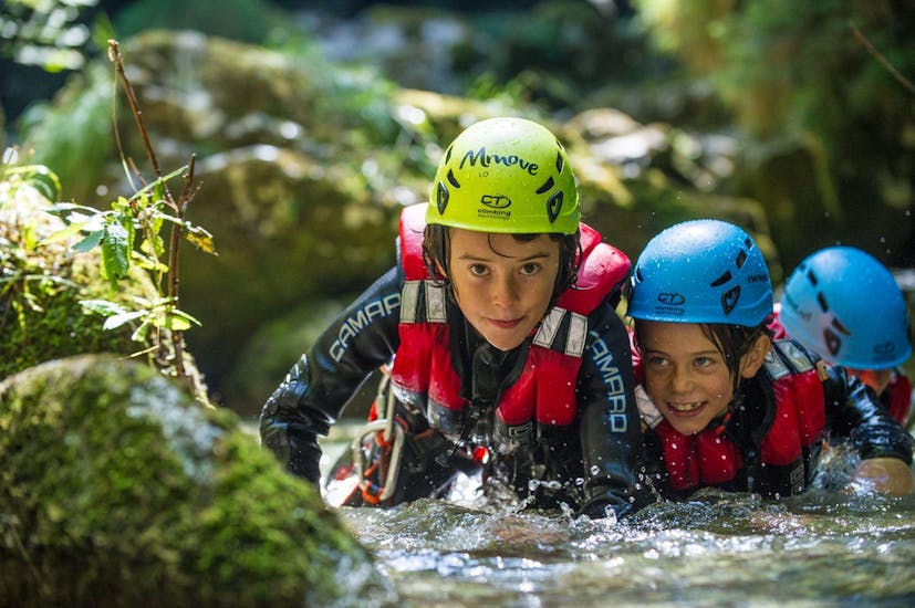Deux enfants grimpent sur un rocher pendant le canyoning dans le Rio Nero d'Arco pour les familles avec enfants - Into Nature Garda Lake.