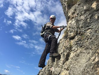 Un partecipante impavido sta scalando la parete di roccia durante la Via Ferrata Monte Albano - Percorso Storico con Mmove - Into Nature Lago di Garda.