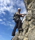 Ein furchtloser Teilnehmer erklimmt die Felswand während des Klettersteigs Monte Albano - Historischer Weg mit Bewegung - Into Nature Lago di Garda.