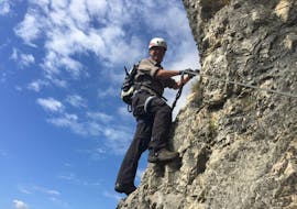 A fearless participant is climbing the rock face during the Via Ferrata Monte Albano - Historical Route with Mmove - Into Nature Lago di Garda.