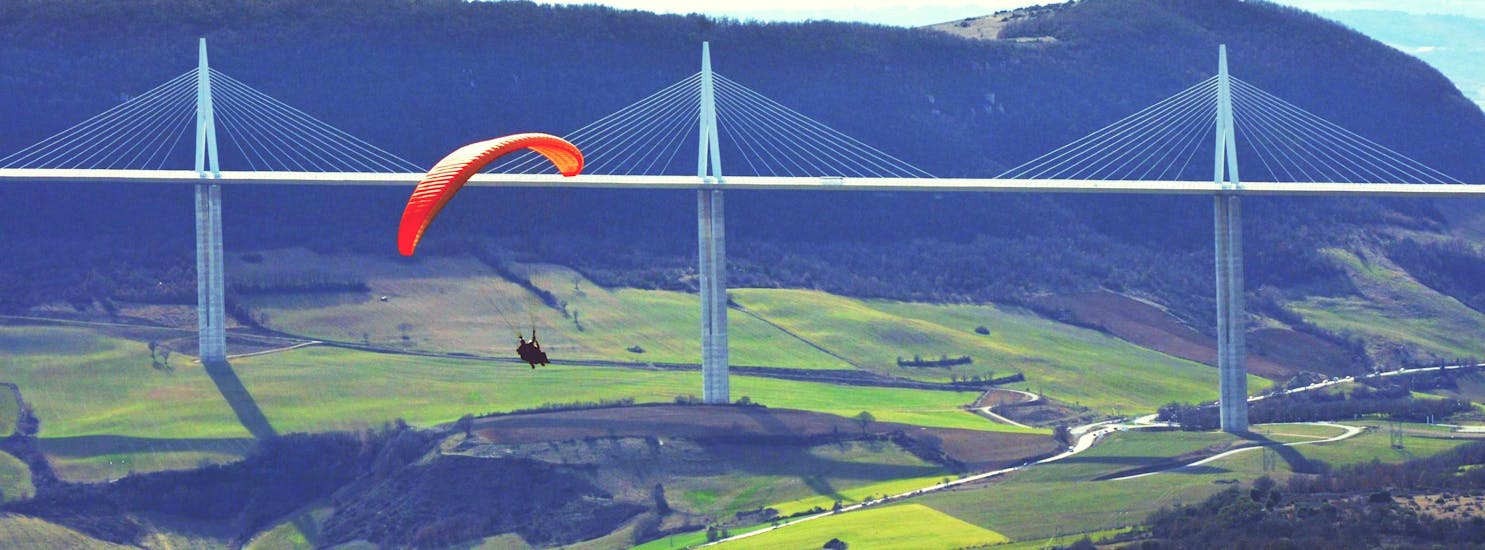 A paragliding pilot from Air Magic Parapente is doing a Tandem Paragliding Flight "Sensation" in front of the Millau Viaduct.
