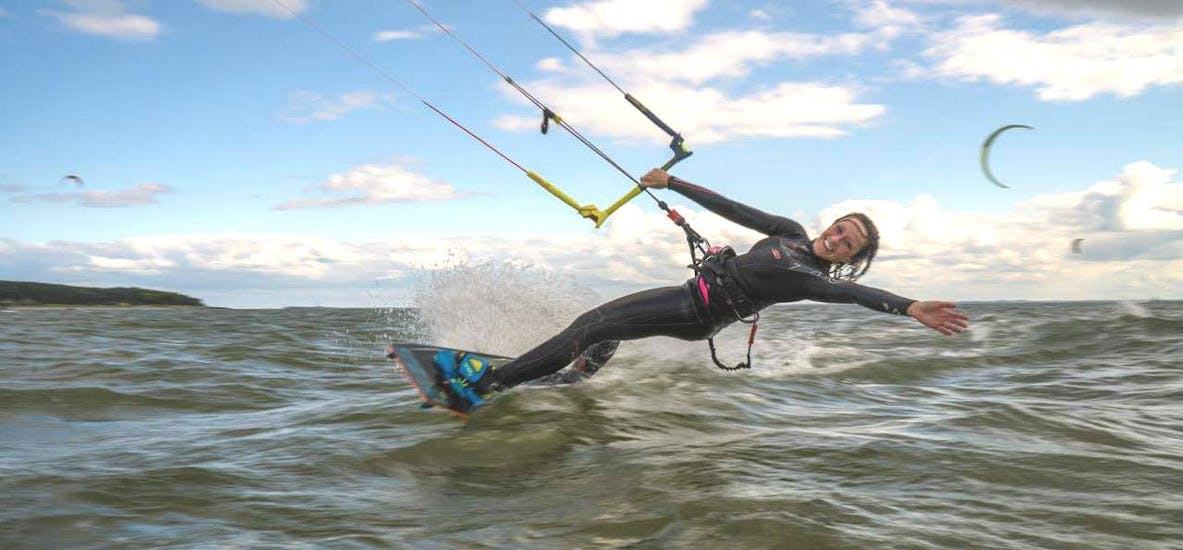 A woman during a trick on her surfboard during Kitesurfing Lessons "Basic Course" in Thiessow with ProBoarding Rügen.