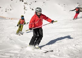 Ein Skilehrer der Ski- und Snowboardschule Vacancia zeigt einem Kind während der Aktivität Privater Kinder Skikurs - Alle Levels die richtige Skitechnik.