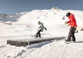 Ein junger Snowboarder übt bei der Aktivität Privater Snowboardkurs für Kinder - Alle Levels mit der Ski- und Snowboardschule Vacancia neue Tricks.