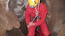 Una persona mentre avanza dentro una grotta, durante l'attività di speleologia a Spectaclan per le famiglie con Geo Ardèche Canyon.