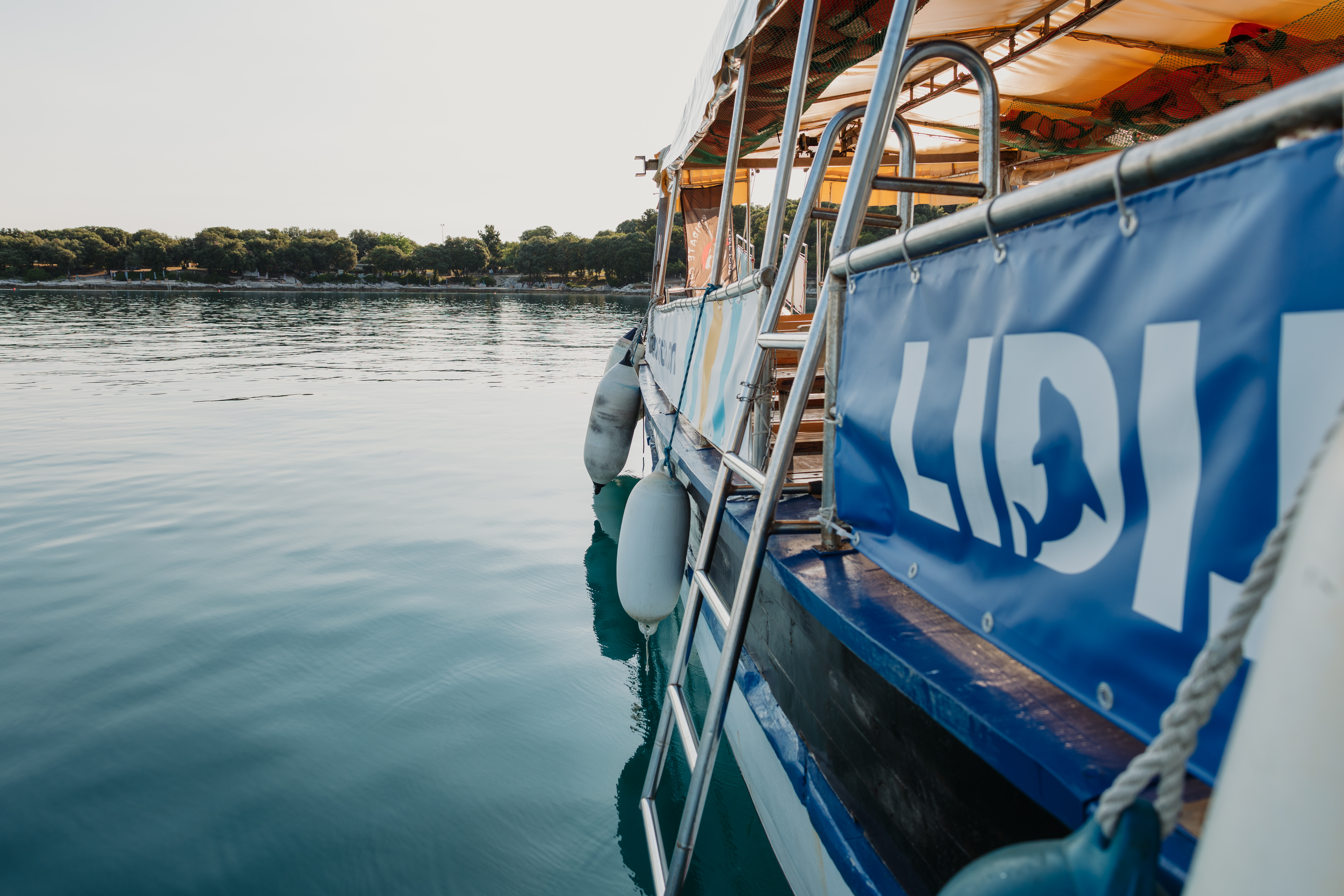Lidija Tours boat trip along a scenic coastline The Lidija Tours Vrsar boat is seen on the calm water during a boat trip from Vrsar to Rovinj and Lim Fjord.