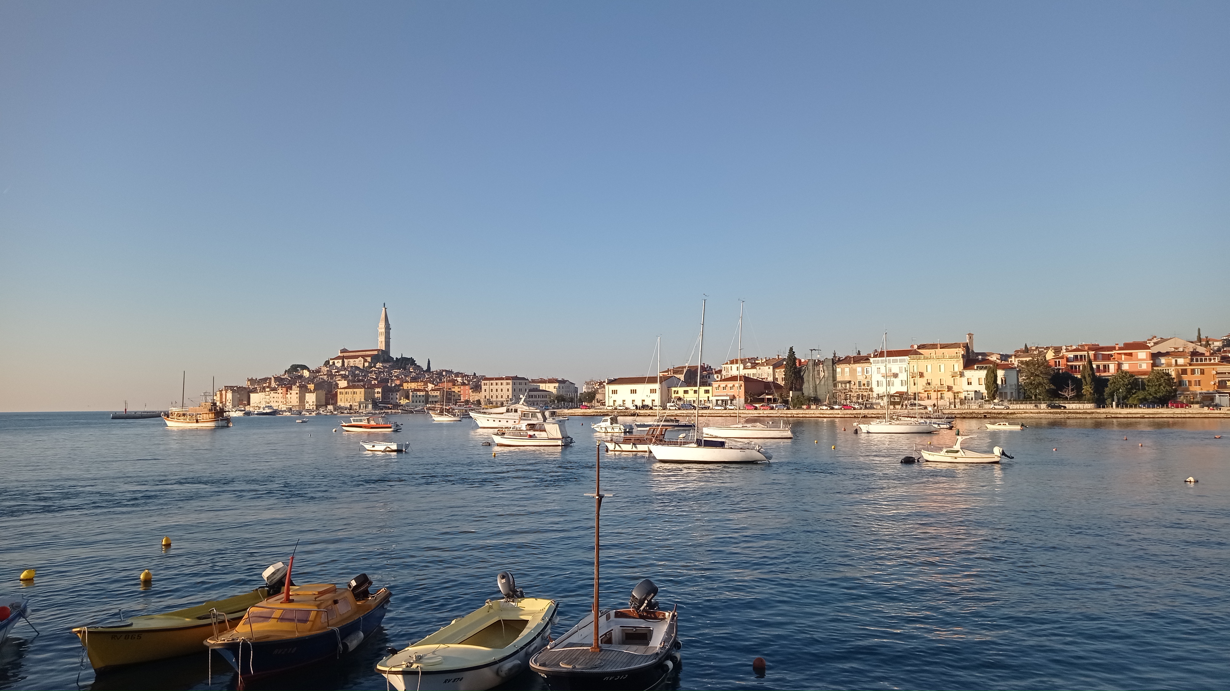 Blick auf die Altstadt von Rovinj von einer Bootsfahrt aus Ein malerischer Blick auf die Altstadt von Rovinj und ihren mit Booten gefüllten Hafen im warmen Licht der untergehenden Sonne, gesehen auf einer Bootsfahrt von Vrsar nach Rovinj und zum Limfjord mit Lidija Tours Vrsar.