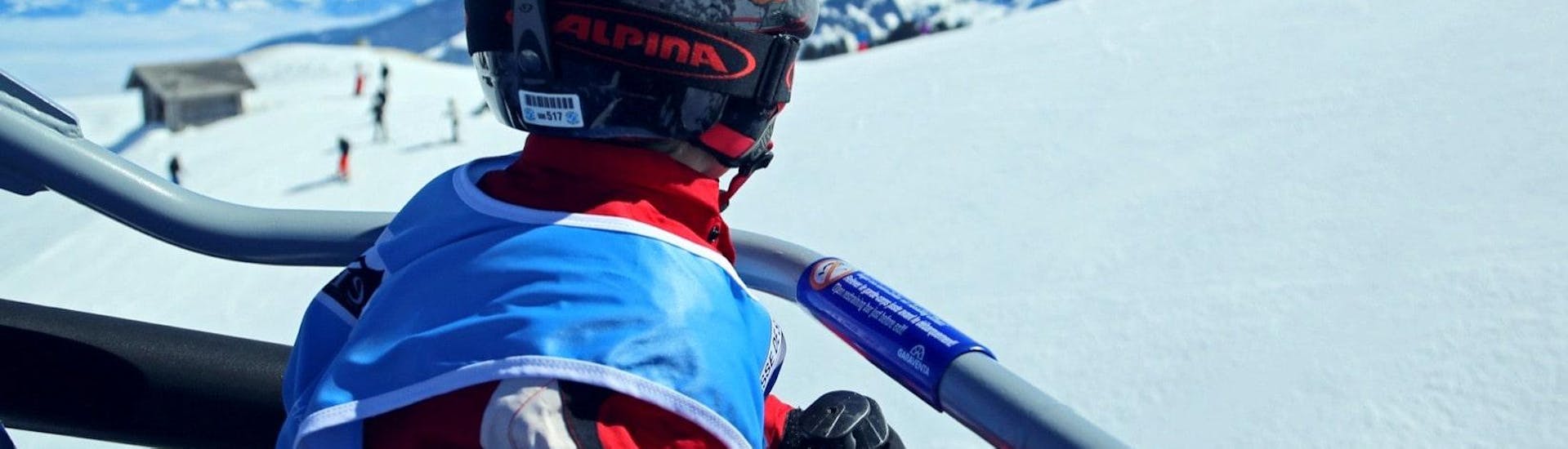 Un enfant est assis dans un siège de remontées mécaniques en route pour son Cours particulier de ski pour Enfants - Tous âges avec l'École Suisse de Ski Crosets-Champoussin.
