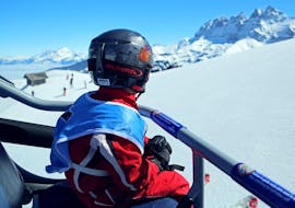 A young child is sitting in a chairlift on his way to his Private Ski Lessons for Kids - All Ages with the Swiss Ski School Les Crosets-Champoussin.