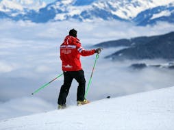 A ski instructor from the Swiss Ski School Les Crosets-Champoussin is standing at the top of a mountain during a Private Ski Lessons for Adults - All Levels.