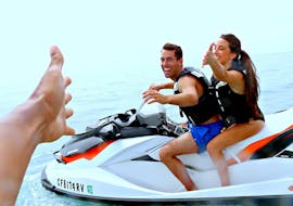 Two people try to reach the hand of our partner JetSki Safari Split's guide on a jet ski during their jet ski safari to the Čiovo island from Split.