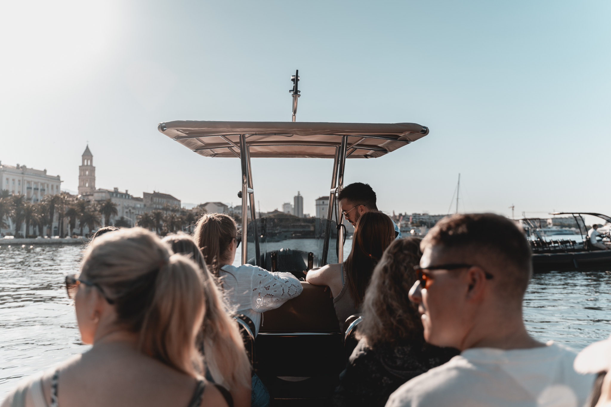 Een groep toeristen geniet op een speedboot van het zonnige uitzicht op de kustlijn van Split tijdens een boottocht langs 6 eilanden vanuit Split, inclusief de Blauwe Grot en Hvar, georganiseerd door Toto Travel Split.