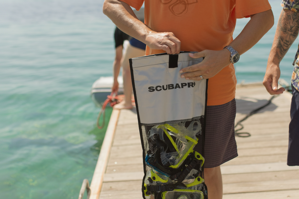 A man holds a bag of snorkeling equipment on a wooden pier before embarking on the 3 Islands and Blue Lagoon Boat Trip from Split with Toto Travel Split.