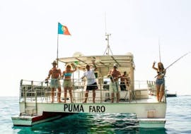 The passengers of the Boat Tour to the Rocks and Caves of Benagil from Vilamoura organized by Cruzeiros da Oura Vilamoura are waving at the camera as they are heading to sea.