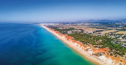Aerial view of the stunning Algarve coastline from Vilamoura An aerial view of the Algarve coastline with its red cliffs and turquoise water, as seen on the Boat Trip - Benagil Caves & Coastline from Vilamoura with AlgarExperience.