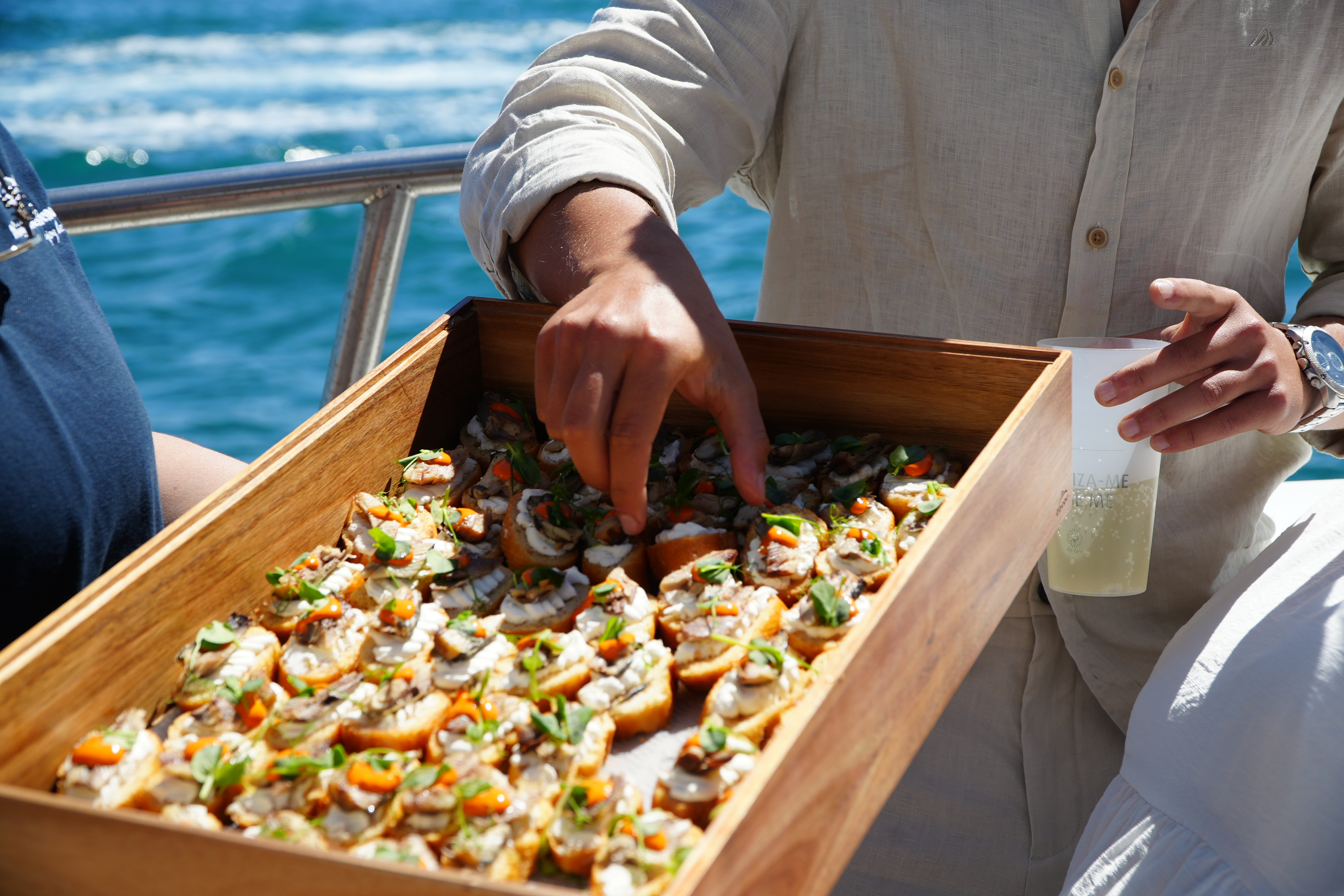 Durante la excursión en barco Vilamoura - Brunch y Cuevas de Benagil con barra libre, organizada por AlgarExperience, un cliente selecciona un aperitivo fresco de una bandeja de madera.