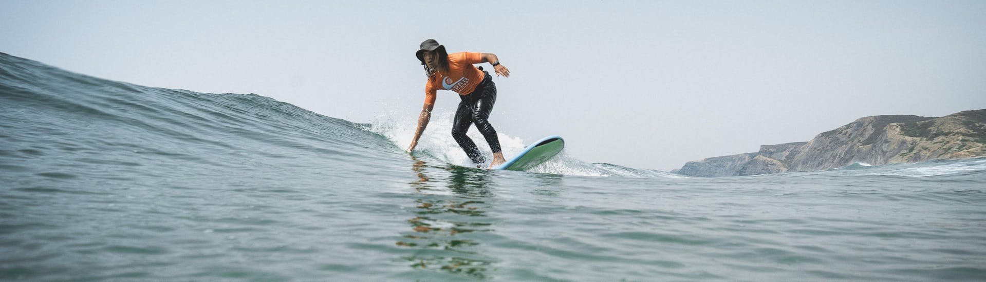 Ein Teilnehmer reitet eine kleine Welle während des privaten Surfunterrichts (ab 6 Jahren) am Praia Castelejo mit der Good Feeling Surf School Algarve.