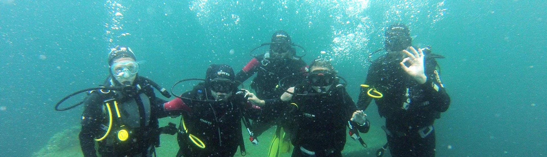 A group of friends are posing underwater during their PE12 & SSI/PADI Scuba Diver Course for Beginner with Le Kalliste Plongée.