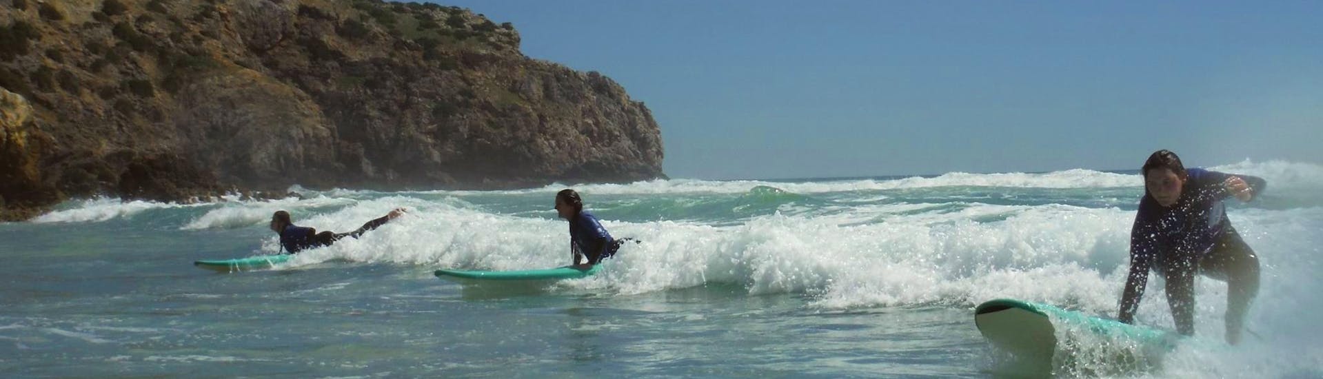 Drei junge Frauen reiten beim Surfkurs für Ein- und Aufsteiger in der Algarve mit Extreme Algarve Surf die Wellen des Atlantiks.
