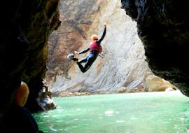 A participant of the Coasteering "Adventure" Tour in Sagres from Poseidon Adventure joyfully performs a jumping trick into the crystal clear water of the Atlantic.