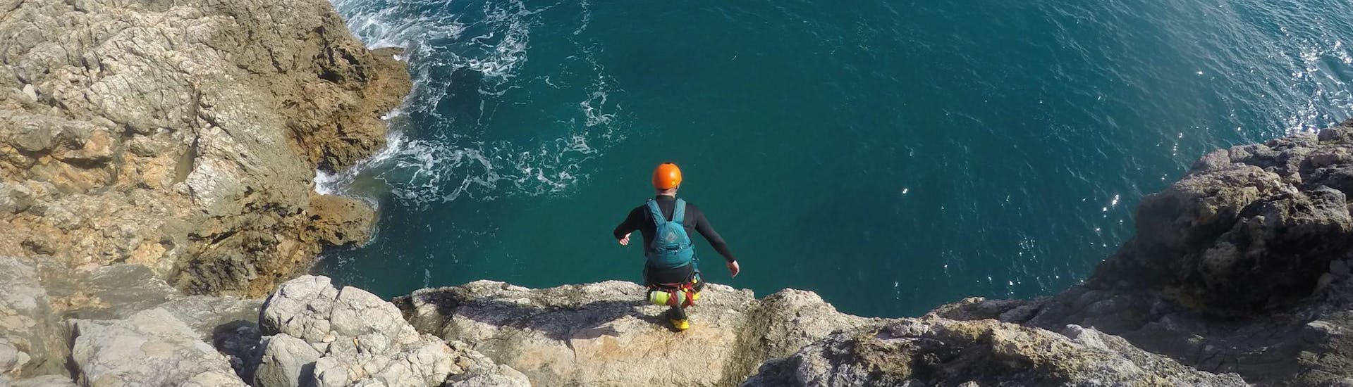 A man jumping off a high cliff on his Coasteering Adventure in Sagres on the side of an experienced guide from Poseidon Adventure.