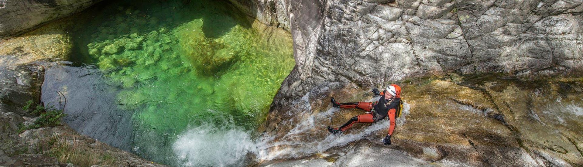 Una ragazza sta scivolando nel Canyon de Zoicu durante l'attività di Canyoning Classico con il loro istruttore di Canyon Corse.