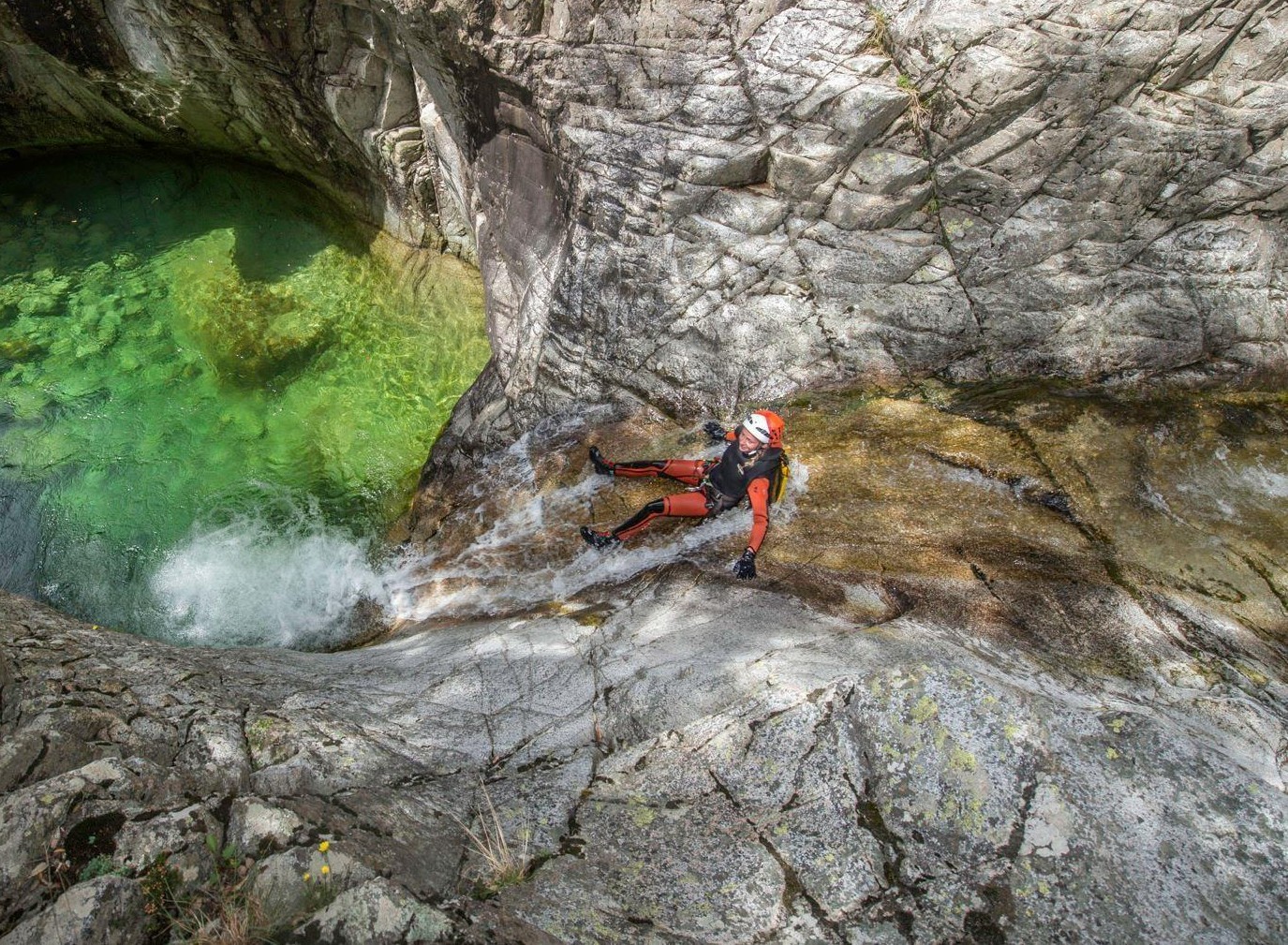 A mother slides in the Zoicu Canyon during the Canyoning activity for families with their instructor from Canyon Corse.